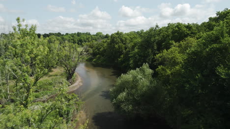 Beautiful-fast-aerial-shot-flying-above-Zumbro-river-surrounded-by-trees,-USA