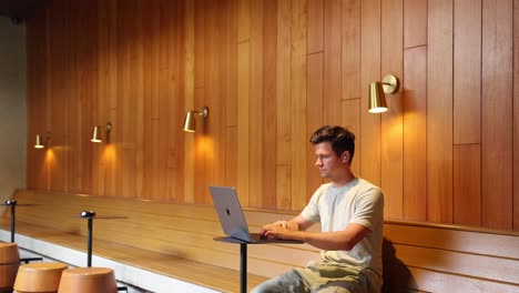 Young-Adult-Man-Working-On-Apple-Laptop-Inside-Cozy-Coffee-shop