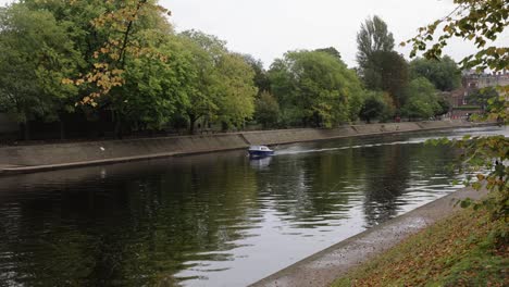 Wide-angle-tracking-shot-of-a-small-boat-travelling-along-the-river-ouse-in-York