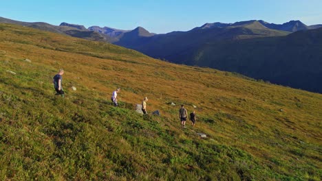 Aerial-over-group-of-hikers-on-the-rugged-hills-near-Svyde-in-the-Vanylven-Municipality,-Norway