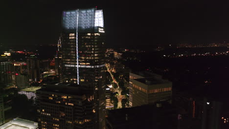 Aerial-slide-and-pan-shot-of-modern-skyscraper-with-illuminated-roof