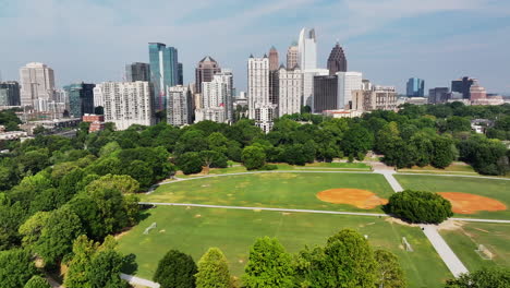 Aerial-sliding-reveal-of-sports-fields-in-park-and-tall-midtown-skyscrapers-in-background