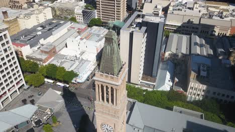 Aerial-circling-Brisbane-city-hall-clock-tower-on-sunny-day,-Australia