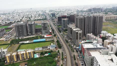 Cámara-Aérea-De-Drones-Que-Pasa-Por-El-Centro-De-La-Ciudad-De-Rajkot-Desde-Una-Altura-Muy-Alta-Con-Edificios-Altos-Al-Frente-Y-Edificios-Bajos-Al-Fondo