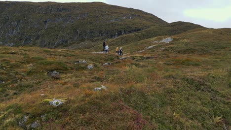 Aerial-towards-hikers-on-the-rugged-hills-near-Vanylven-Municipality,-Norway