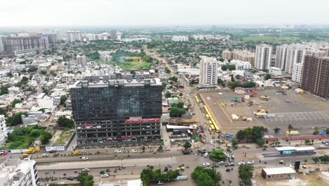Aerial-top-view-of-Rajkot-city,-ring-road-going-from-the-center-of-the-city-with-high-rise-buildings-rising-to-the-sky-on-all-sides