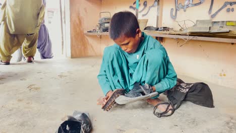 Young-Boy-Polishing-Slippers-On-Floor-In-Pakistan