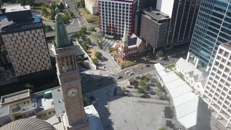 Aerial-towards-Albert-Street-Uniting-Church,-passing-Brisbane-city-hall-tower-clock