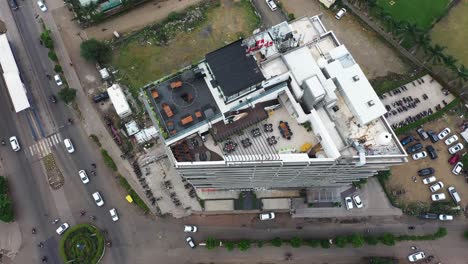 An-aerial-drone-camera-is-following-a-tall-building-with-an-open-terrace-garden-on-the-top-floor