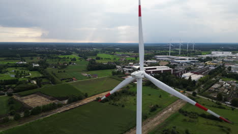 Massive-wind-turbine-spin-on-cloudy-stormy-day,-close-up-aerial-view