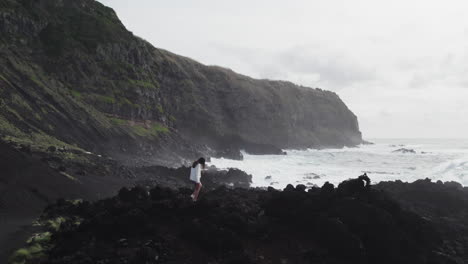 Woman-by-rocky-coast,-Azores,-Ponta-da-Ferraria-waves-crashing