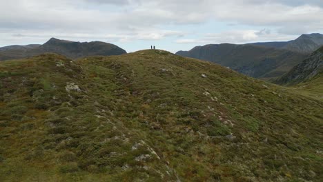 Antena-Hacia-Los-Excursionistas-En-Las-Escarpadas-Colinas-Cerca-Del-Municipio-De-Vanylven,-Noruega