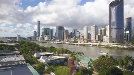 Aerial-rising-from-South-Bank-Parklands-revealing-Brisbane-river-and-CBD,-Australia
