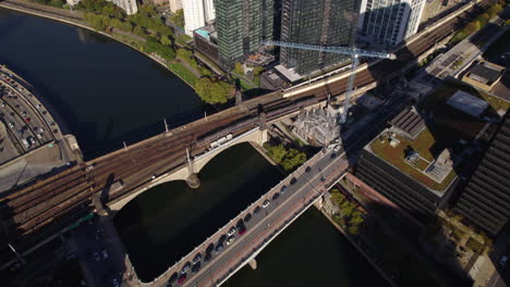 Aerial-view-following-a-train-on-the-Pennsylvania-Railroad,-Connecting-Railway-Bridge,-in-sunny-downtown-Philadelphia