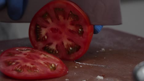 Un-Chef-Cortando-Un-Tomate-En-Rodajas,-Lenta-Y-Cuidadosamente,-Con-Un-Cuchillo-Profesional-Afilado