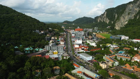 Panoramic-aerial-view-of-Ao-Nang-coastal-town-surrounded-by-limestone-cliffs-and-mountains,-Scenic-driving-trail-in-Krabi,-Thailand