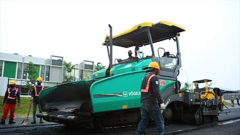 Los-Trabajadores-Están-Utilizando-La-Terminadora-De-Pavimentadora-De-Asfalto-Para-Esparcir,-Nivelar-Y-Compactar-La-Mezcla-Asfáltica-En-Caliente-Para-Hacer-Capas-Base,-Aglutinante-Y-Superficial-Para-La-Construcción-De-Carreteras-Asfálticas.