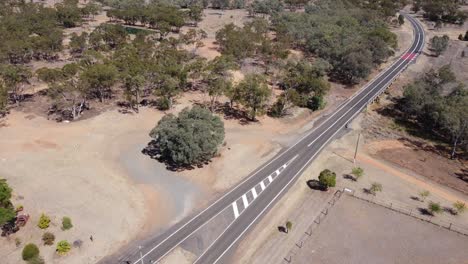 Drone-Volando-Hacia-Un-Estanque-De-Agua-Sobre-Una-Carretera-Rural-En-El-Interior-De-Australia