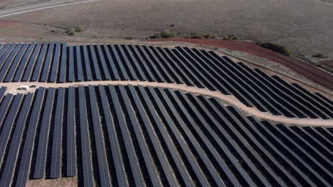 Incline-Hacia-Abajo-El-Dron-Sobre-El-Parque-Solar-Fotovoltaico,-Paneles-De-Fila-De-Granja,-Colinas-Panorámicas-Hacia-Abajo