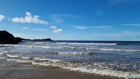 Relaxing-slow-motion-waves-washing-across-peaceful-paradise-green-Anglesey-island-coastline