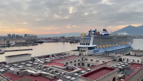 Scene-of-a-Quantum-Ultra-class-cruise-ship,-namely-Royal-Caribbean-docking,-against-the-background-of-a-soft-glow-sunrise-in-Naples,-Italy