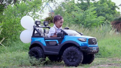 Isoliertes,-Süßes-Baby,-Kleinkind,-Das-In-Einem-Spielzeugauto-In-Weißem-Stoff-Sitzt-Und-Luftballons-Im-Freien-Spielt.-Das-Video-Wurde-Am-4.-August-23-In-Jodhpur,-Rajasthan,-Indien,-Aufgenommen