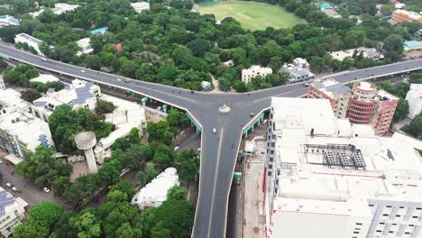 Aerial-view-of-Rajkot-city-with-fly-over-bridge-connecting-three-side-roads-and-reducing-traffic,-high-rise-buildings,-gardens,-and-solar-panels