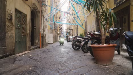 Paseo-En-Moto-Por-Las-Estrechas-Calles-De-Nápoles-Decoradas-Con-Atributos-Futbolísticos