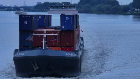 Drone-Reveal-Shot:-Big-Cargo-Ship-"Casa-Blanca"-Sailing-Through-Moerdijk-full-of-Containers-at-Dusk