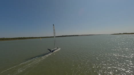 FPV-aerial-spins-around-catamaran-sailboat-under-sail-in-ocean-lagoon