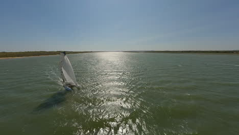 FPV-aerial-quickly-orbits-catamaran-sailboat-sailing-on-ocean-lagoon