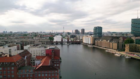 Experimente-El-Encanto-De-Berlín-Desde-Los-Cielos-Mientras-Un-Dron-Se-Desliza-Con-Gracia-Sobre-El-Río-Spree,-Enmarcando-El-Icónico-Puente-Oberbaum-Y-El-Cautivador-Horizonte-De-La-Ciudad.