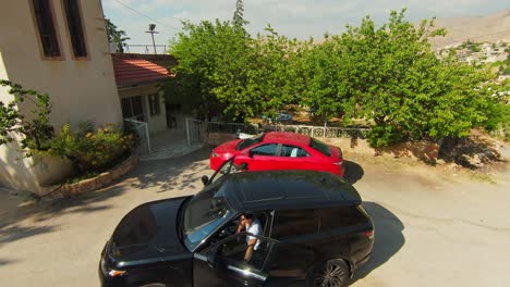 Aerial-circling-shot-of-men-getting-out-of-car-and-walking-towards-home