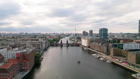 Experimente-El-Encanto-De-Berlín-Desde-Los-Cielos-Mientras-Un-Dron-Se-Desliza-Con-Gracia-Sobre-El-Río-Spree,-Enmarcando-El-Icónico-Puente-Oberbaum-Y-El-Cautivador-Horizonte-De-La-Ciudad.