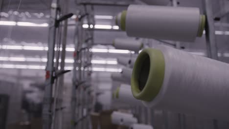 Mid-shot-of-high-tech-machinery-in-factory-weaving-material,-threads-of-fibre-reel