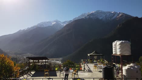 Luftaufnahme-Eines-Männlichen-Reisenden,-Der-Auf-Einem-Hostel-Auf-Dem-Dach-Im-Sangla-Tal-Steht,-Das-Für-Seinen-Roadtrip-Durch-Das-Spiti-Tal-Im-Himalaya-Bekannt-Ist