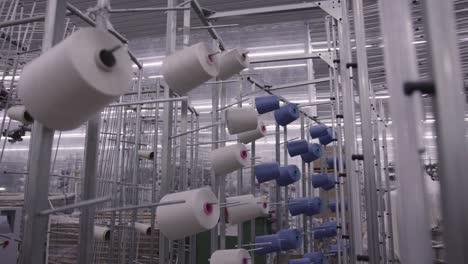 Wide-shot-of-high-tech-machinery-in-factory-weaving-material,-yarns-of-thread