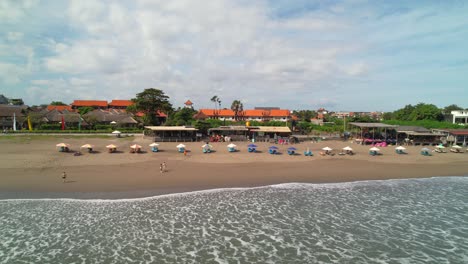 Beachfront-Bars-and-Cafes-in-Batu-Belig-Beach,-Bali-Indonesia---Aerial-Dolly-right