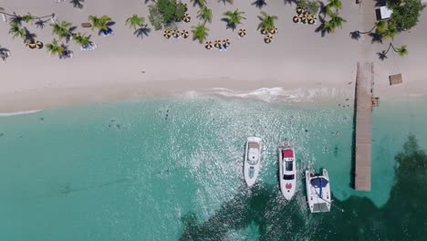 Moored-boats-near-jetty-in-summer-season-on-Catalina-tropical-island-beach-with-turquoise-sea-water-in-Dominican-Republic