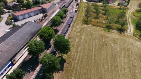 Steam-train-from-Martel-leaving-the-SNCF-station-with-tourists,-smoke-coming-out-of-the-locomotive,-aerial-view-in-summer,-Lot,-France
