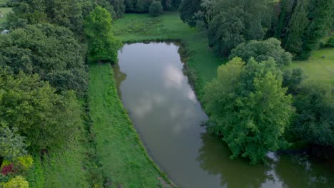 Aerial-drone-view-of-small-rectangular-shaped-lake-in-lush-green-forest-of-Brittany-in-France