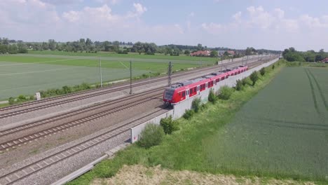 Red-DB-train-drives-through-scenic-german-landscape,-aerial-follow-pan-right