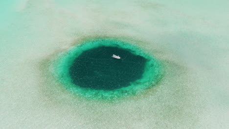 Hohe-Luftaufnahme-Des-Blue-Hole-Mit-Vor-Anker-Liegendem-Fischerboot,-Bahamas