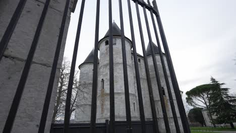 Castle-fortress-in-view-behind-metal-fenced-bars-on-cloudy-overcast-day