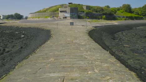 Dolly-in-on-cobblestone-breakwater-with-dune-bunker-in-background