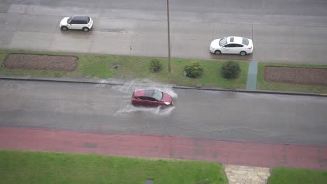 Top-Down-View-Of-Car-Driving-By-Flooded-Street,-Punta-Del-Este,-Uruguay