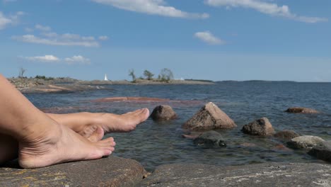 Woman-feet-by-the-sea-on-rocky-shore-island