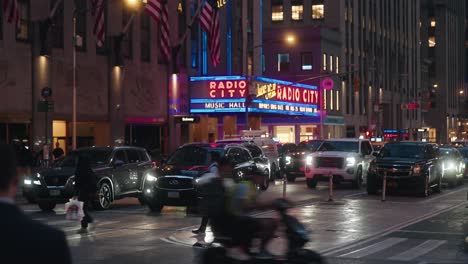 Radio-City-Music-Hall-neon-sign-lights,-busy-intersection-at-night