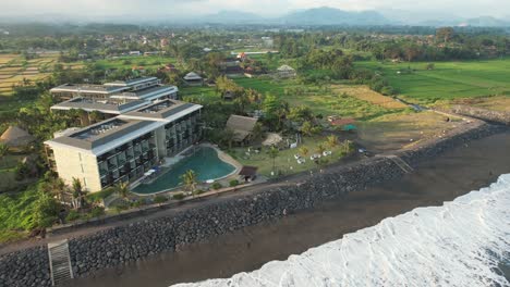 Antena-Reveladora-Wyndham-Tamansari-Jivva-Resort-Bali-Con-Pintorescas-Montañas-Y-Tierras-De-Cultivo-Como-Telón-De-Fondo-En-Klungkung-Bali,-Indonesia---Despegue-De-Drones
