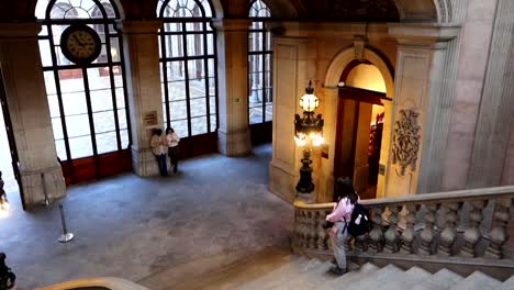 Woman-going-down-main-staircase-of-Palacio-da-Bolsa-in-Porto-during-a-visit